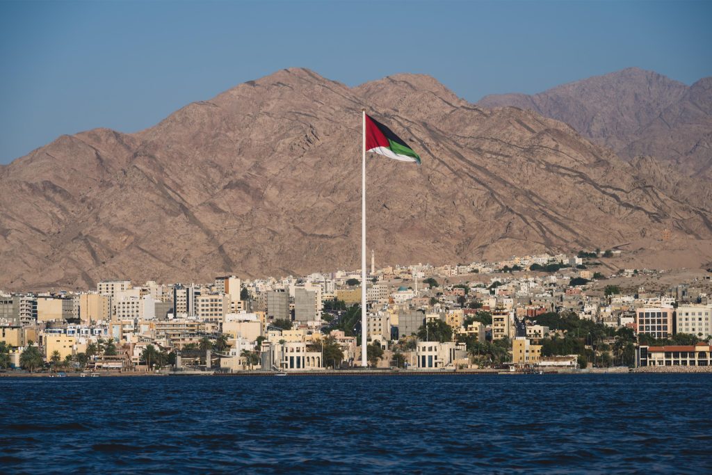 landscape of aqaba with the jordanian flag in the center and mountains in the background